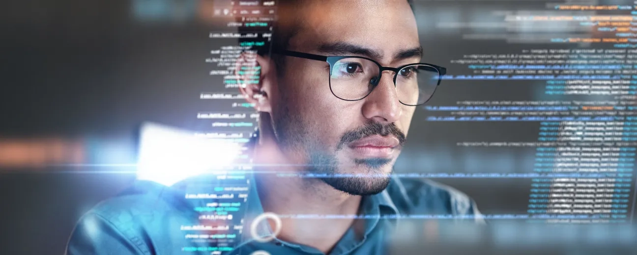 Person with glasses looking at computer screen with code and digital interface elements overlaid