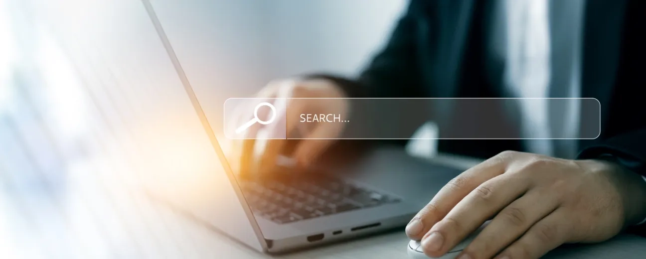 Person using a laptop and mouse with a search bar overlay, representing website navigation.