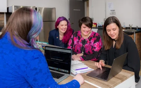 women using laptops and smiling
